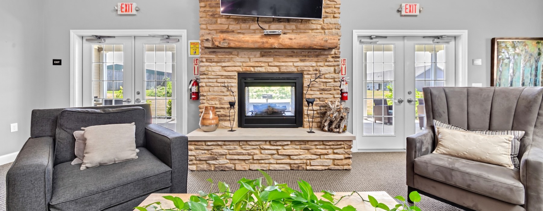 a clubroom with a tv, fireplace and chairs